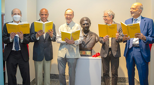 Speakers pose in front of statue