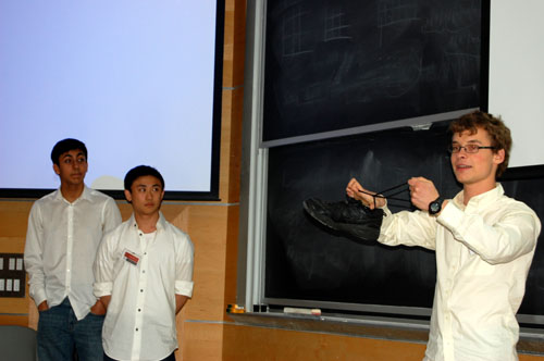 PRIMES reading group students Rohil 
            Prasad, Isaac Xia, and William Kuszmaul. Kuszmaul is 
            explaining the concept of trefoil, using his shoelaces.